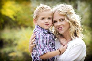A young mother is outside taking a picture with her toddler son.