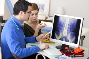 A male and female are sitting down in front of a screen looking at an x-ray
