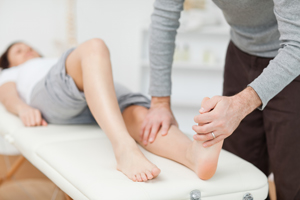 Physical Therapist is helping a female patient stretch her lower leg and foot