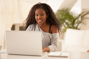 A female is sitting in front of an open laptop